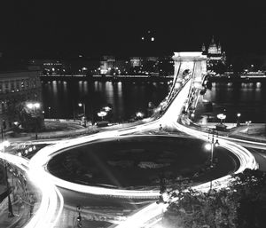 Light trails on road by illuminated city at night
