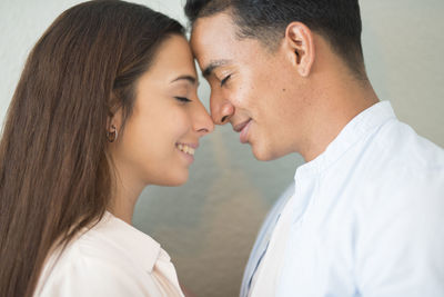 Happy young couple standing against wall