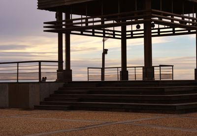 Staircase by sea against sky during sunset