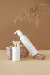 White blank cosmetic bottles, dried herbs on stone podiums. natural organic mock-up. face and body.