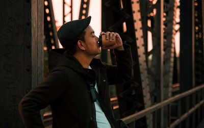 Young man looking away while standing outdoors