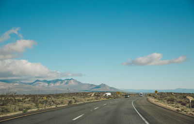 Road by mountains against blue sky