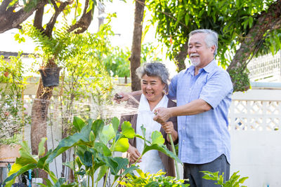 Full length of happy man standing against plants