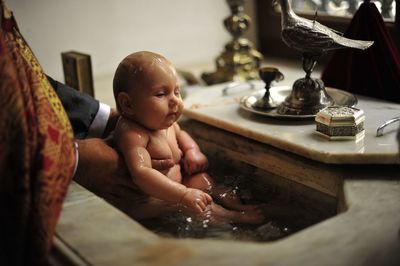 Priest holding baby at baptism