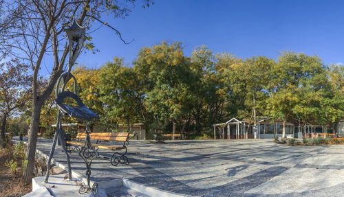 Empty chairs and tables by trees against sky