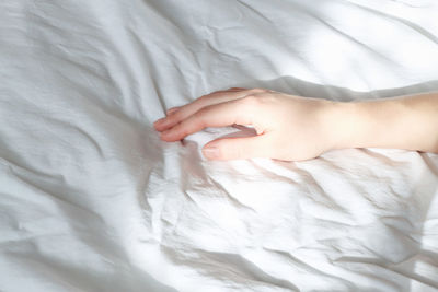 A woman's hand on the bed in the morning sun.