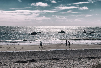 Silhouette people on beach against sky