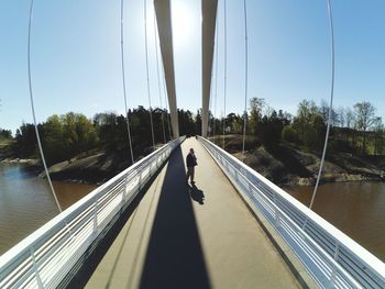 Woman walking on bridge against sky