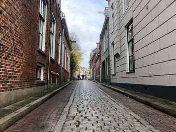 Surface level of footpath amidst buildings against sky