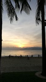 Silhouette people on beach at sunset