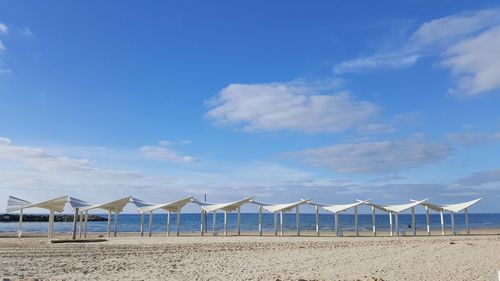 Deck chairs on beach against blue sky