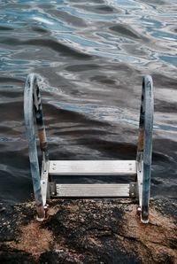 High angle view of metallic ladder on rock in lake