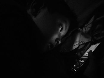Portrait of boy lying on bed in darkroom