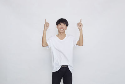 Portrait of smiling young man standing against white background