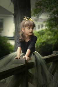Girl sitting on wooden railing at park