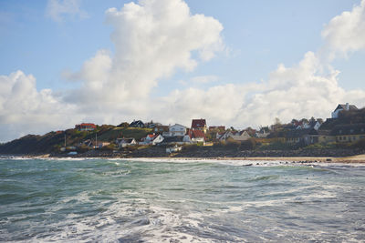 Scenic view of sea by buildings against sky