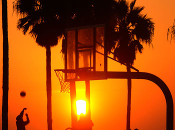 Silhouette palm trees against orange sky