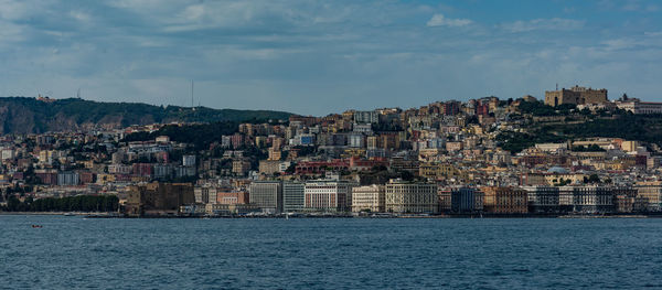 Sea by cityscape against sky