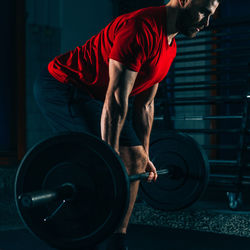 Male athlete exercising with barbell in gym