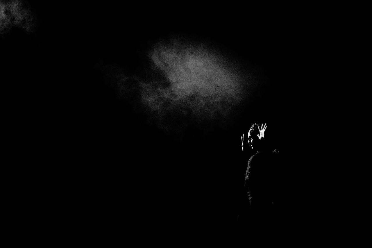 one person, smoke - physical structure, dark, night, silhouette, copy space, real people, men, lifestyles, warning sign, black background, risk, social issues, activity, leisure activity, indoors, holding, bad habit, communication, nightlife