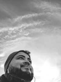 Low angle portrait of young man looking away against sky