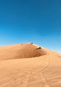 Sand dunes in desert against clear blue sky