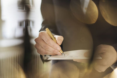 Hand of businessman writing with golden fountain pen on notepad