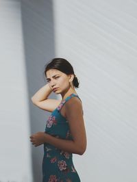 Woman looking away while standing against wall