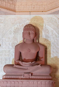 Isolated red stone jain god holy statue in meditation from different angle