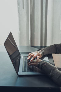 Woman working remotely on her laptop computer managing her work sitting at the table in a cafe