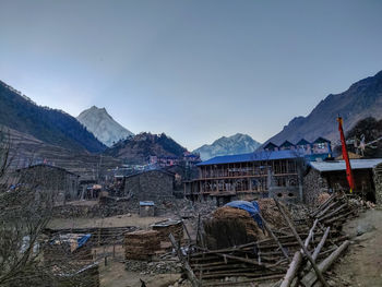 Houses by mountains against clear sky