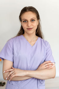 Portrait of young woman standing against white background