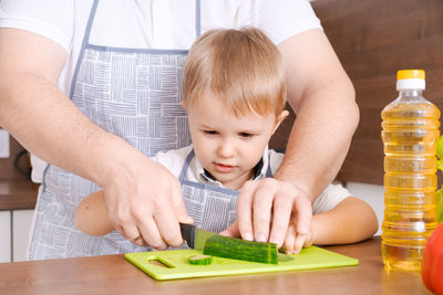 Father and son at home standing in the kitchen together, man smiling