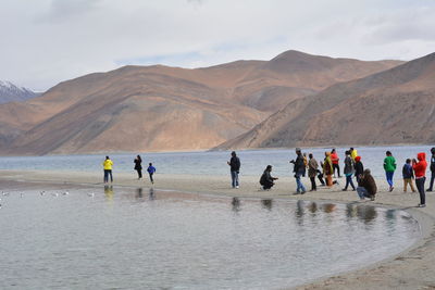 People at shore of pangong lake against mountains