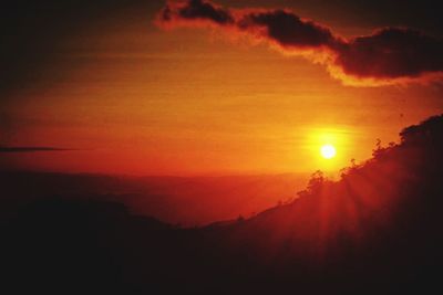 Scenic view of silhouette mountains against orange sky