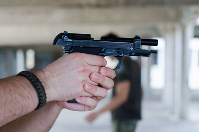 Cropped hands holding gun by man