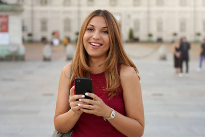 Portrait of smiling young woman using mobile phone