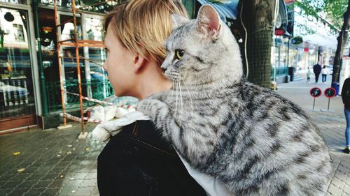 Close-up of teenage boy with cat in city 