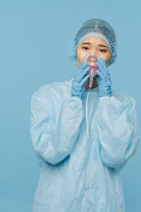 Portrait of woman wearing mask against blue background