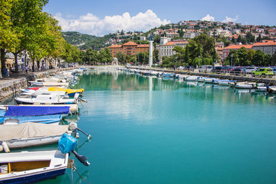 Boats moored in water against sky in city