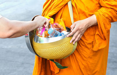 Midsection of monk collecting alms