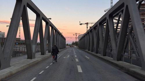 Man walking on bridge in city against clear sky