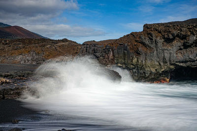 Scenic view of waterfall against sky