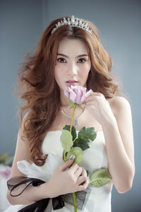 Portrait of young bride with rose wearing tiara at home