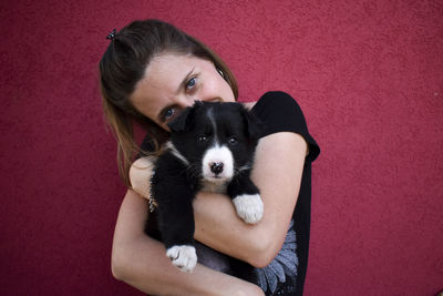 Portrait of woman with dog against red background