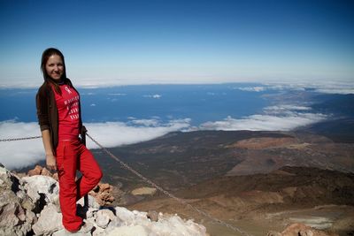 Full length portrait of smiling woman standing on mountain against sky at el teide national park