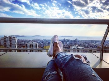 Low section of woman relaxing against sky