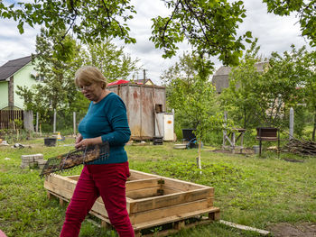 Full length of woman standing against plants in yard