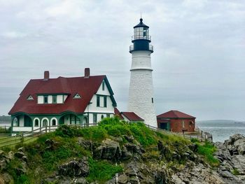 Lighthouse by sea against sky