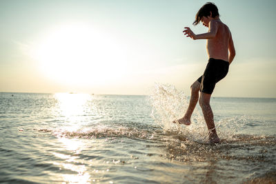 Full length of woman standing at beach against sky during sunset